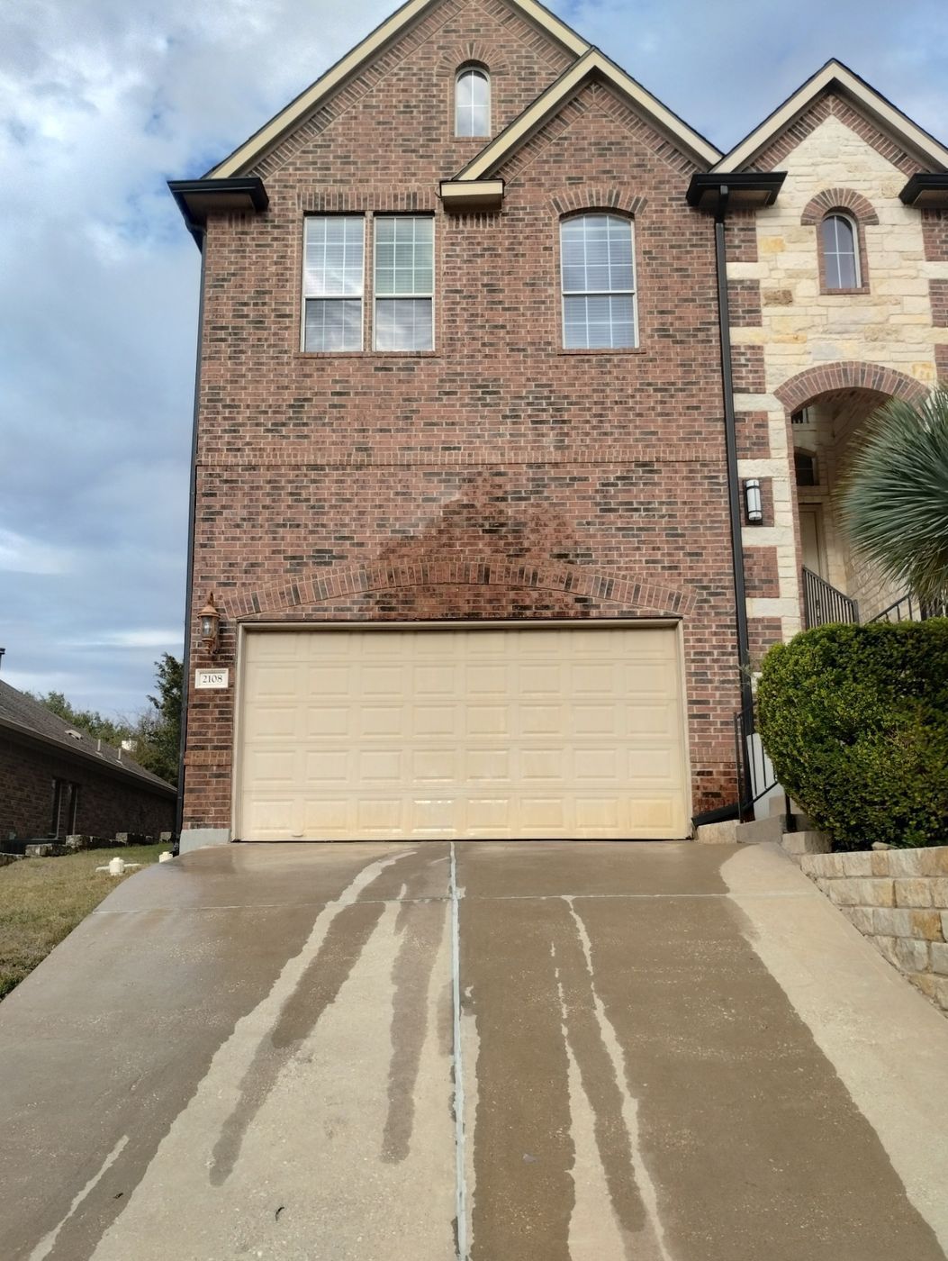 Two-story brick home showing water stains above garage door