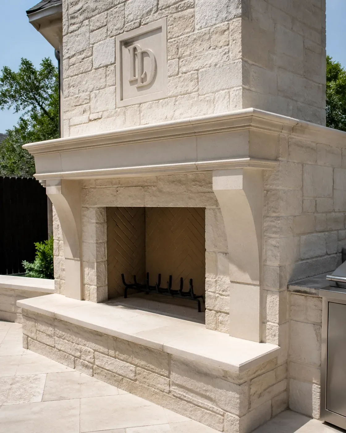 Custom stonework Dallas limestone fireplace with hand-carved details in a luxury outdoor living space.