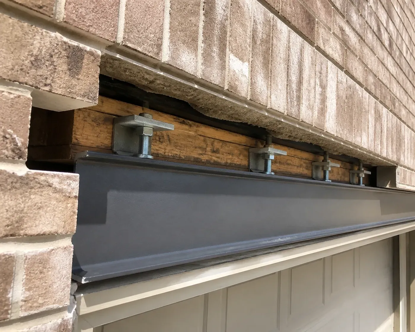 Installing LintelLOCK structural anchors to correct garage lintel rotation in a Dallas home.