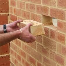 Professional brick replacement showing a technician inserting a matching brick into a masonry wall